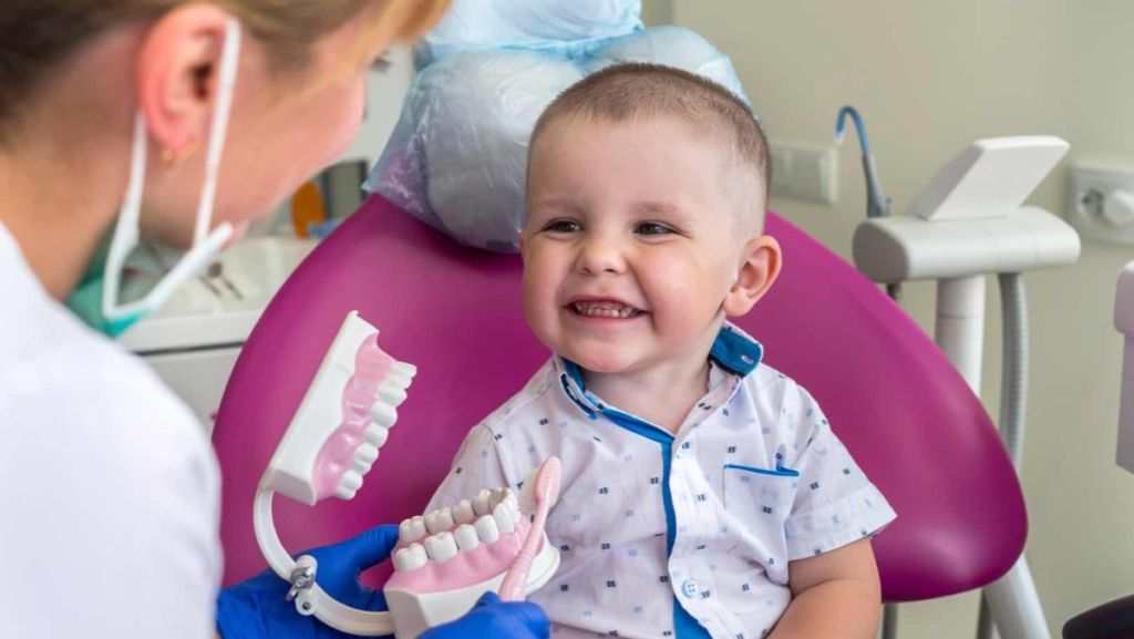 Un petit garçon sourit de toutes ses dents chez le dentiste.