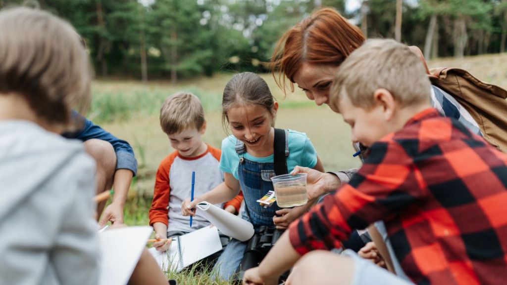 Enfants à l'extérieur entrain d'analyser un pot d'eau