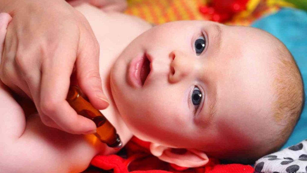 Un roll-on d'huile essentiel est appliqué sur bébé.