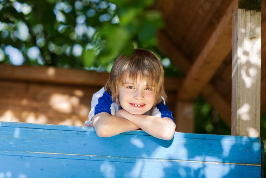 Enfant souriant dans une cabane dans les arbres - crédit photo : contrastwerkstatt via Adobe Stock