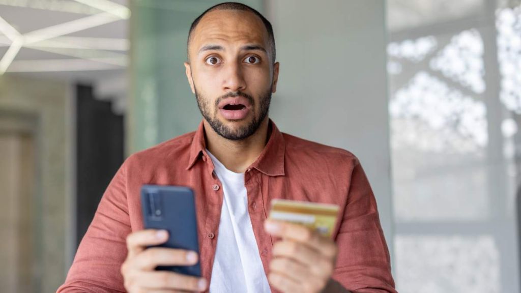 homme surpris au telephone avec sa carte bancaire