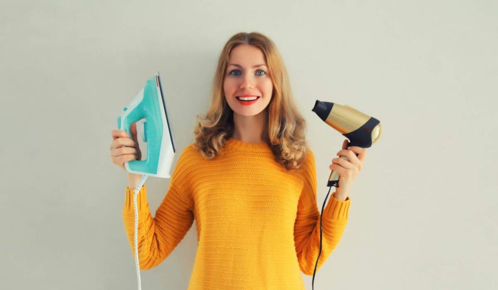 Femme avec sèche-cheveux et fer à repasser - crédit photo : rohappy via Adobe Stock