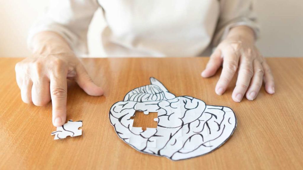 Mains qui retirent un morceau d'un cerveau dessiné, façon puzzle