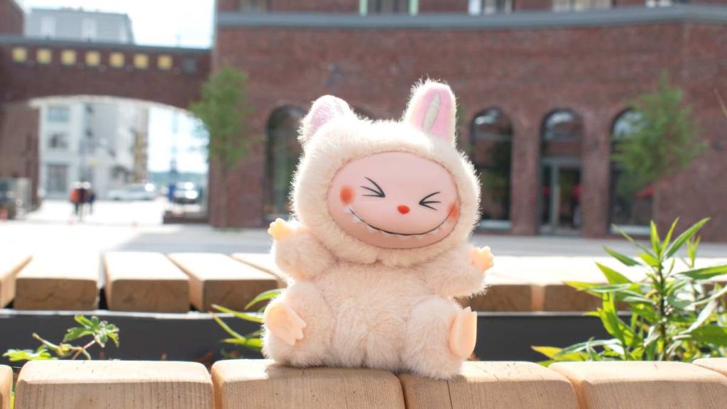 Peluche labubu souriante sur un muret