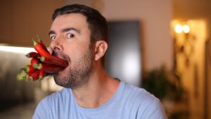 Homme avec des piments rouges dans la bouche