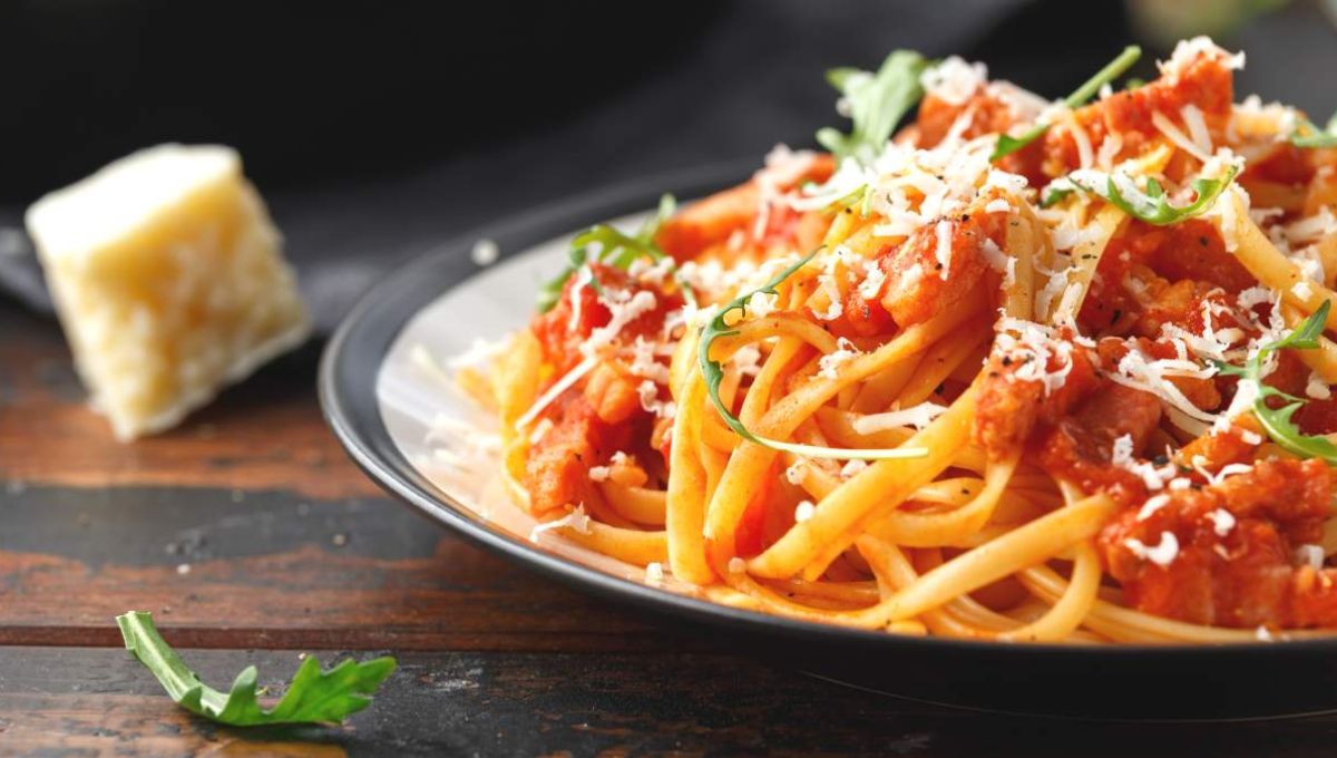 Assiette de pâtes à la sauce tomate avec un morceau de parmesan à côté