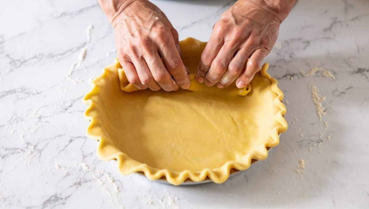 Mains en train de foncer un moule avec une pâte à tarte