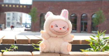 Peluche labubu souriante sur un muret