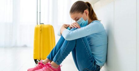 Jeune femme avec un masque à côté de sa valise