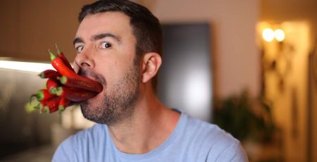 Homme avec des piments rouges dans la bouche