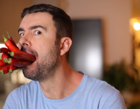 Homme avec des piments rouges dans la bouche