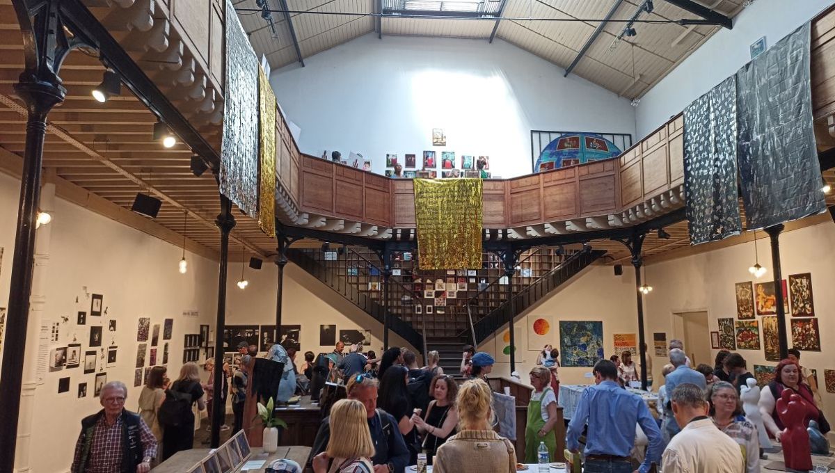 Photo de l'intérieur du Bastille design center. Il s'agit d'une grande pièce avec une importante hauteur sous plafond. L'étage est constitué d'une coursive en bois, sur piliers métalliques, qui fait le tour de la salle.