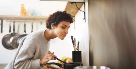 Femme qui cuisine en respirant l'odeur de ses plats