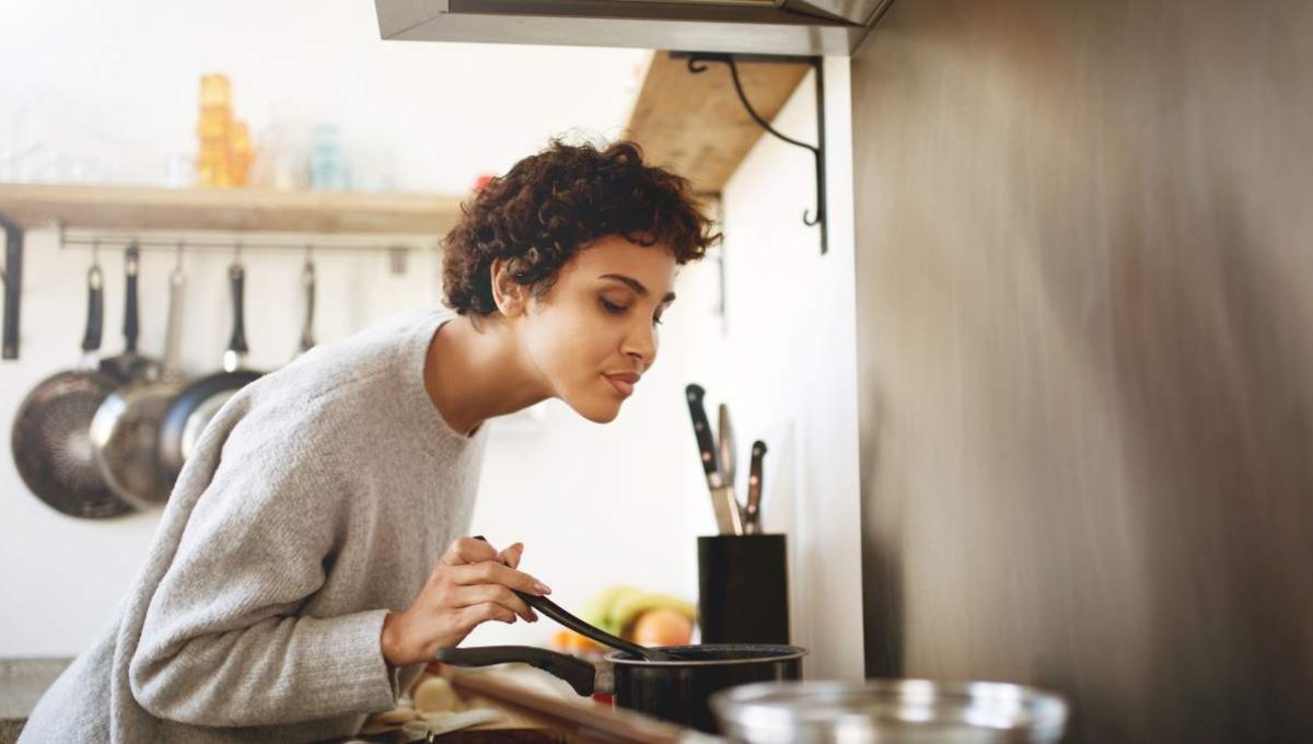 Femme qui cuisine en respirant l'odeur de ses plats