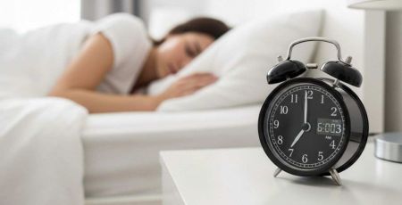 Femme couchée dans son lit avec un gros réveil à côté