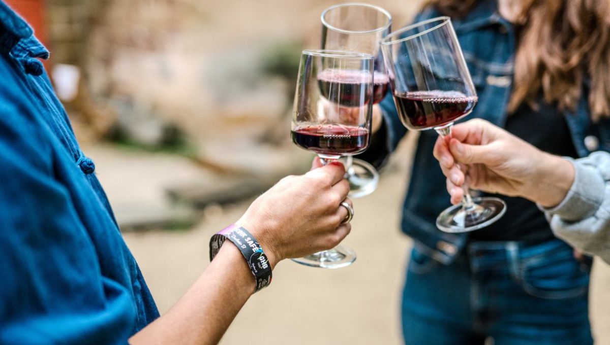 Trois amis trinquent au vin rouge. En premier plan, un bracelet "DRINK SAFE" rappelle l’importance de consommer avec modération, même en plein moment festif.
